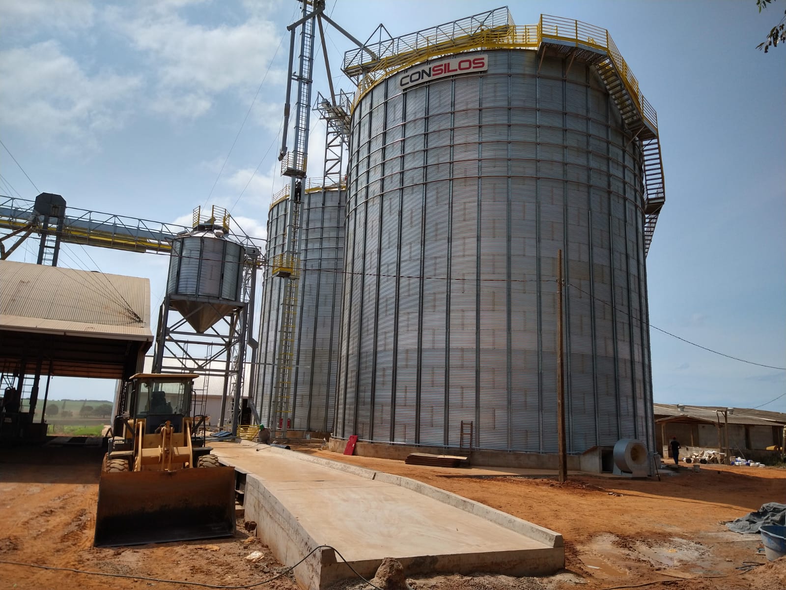 Unidade de armazenagem com silo, moega e pá carregadeira em operação